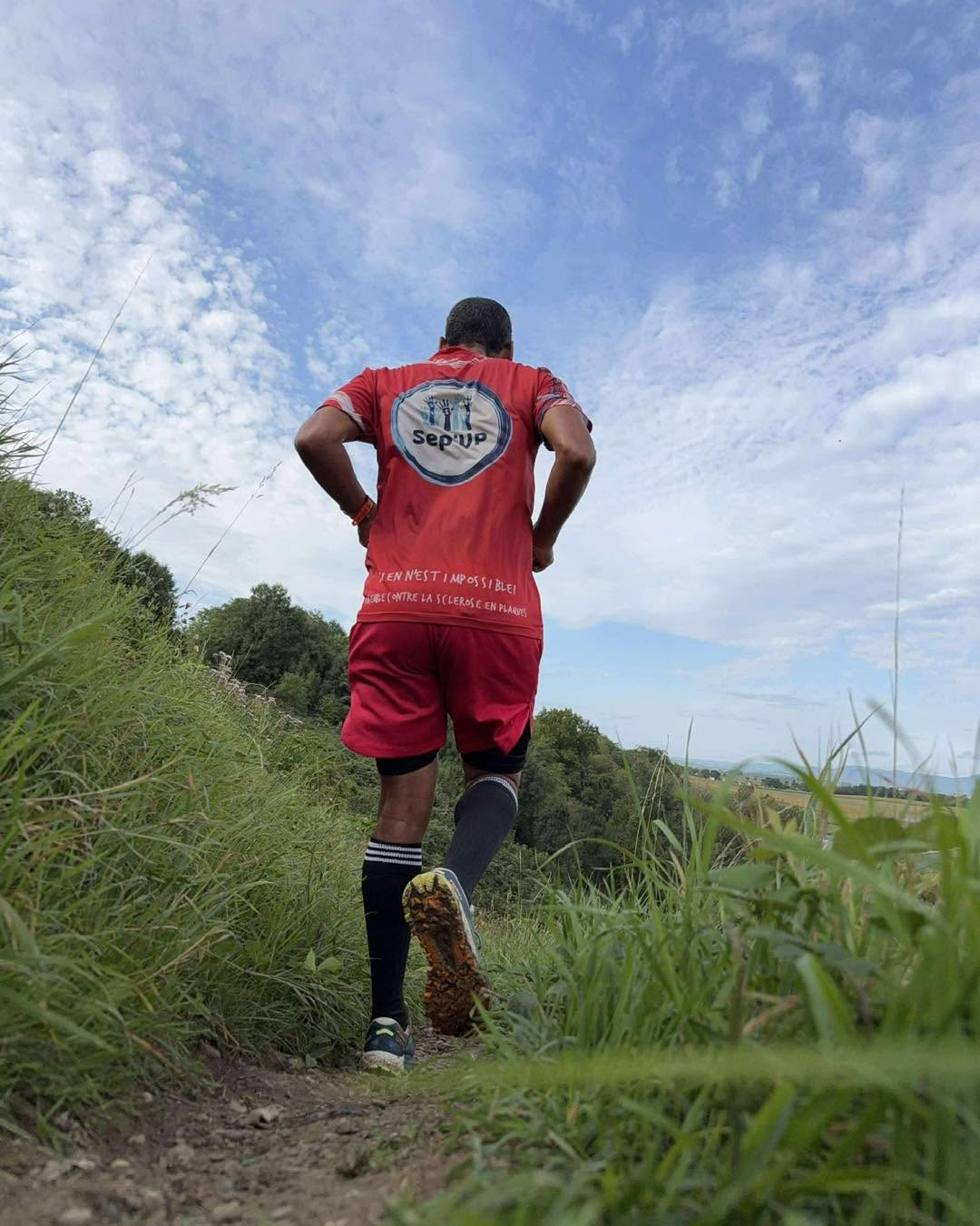Un coureur de la Team Ultra Trail en maillot rouge Sep'UP sur un sentier